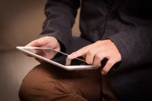 Nahaufnahme: Person bedient ein Tablet, das auf ihrem Schoß liegt