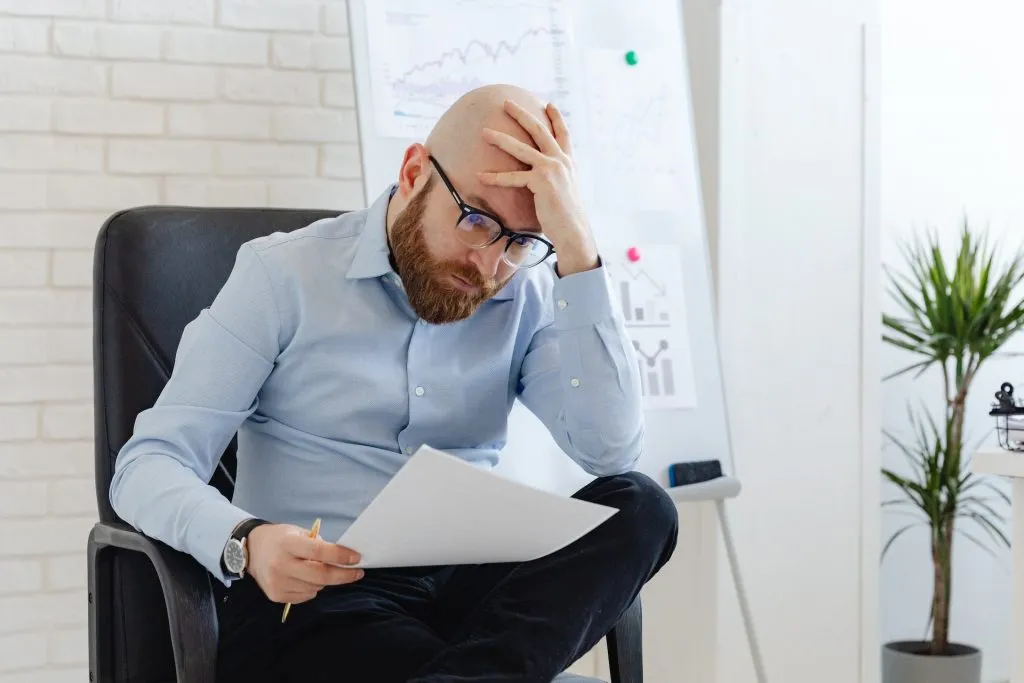 Besorgter Unternehmer sitzt im Büro und prüft ein Schreiben zu Bußgeldern nach einem Arbeitsschutzverstoß